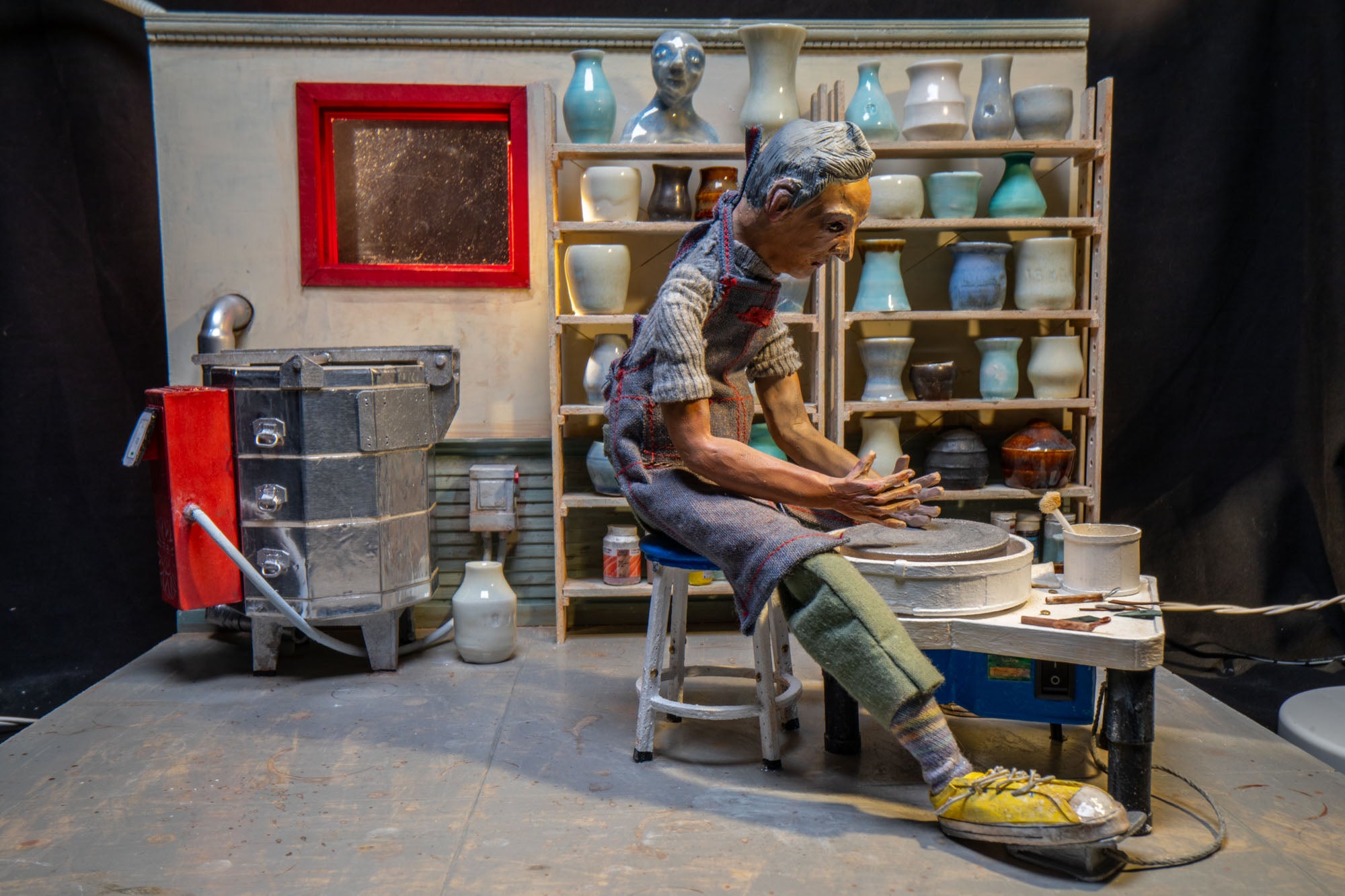 A diorama of a man working a wheel at a pottery studio