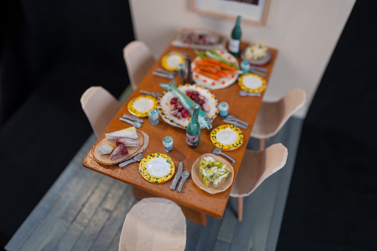 A diorama of chairs surrounding a dining table, which holds food