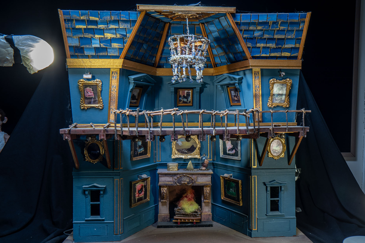 A diorama of the interior of a blue house made from wood and cardboard