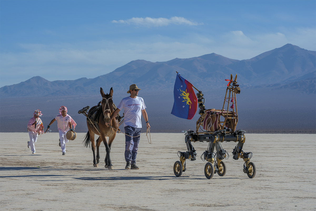 Dancers and a mule led by a local guide accompany Guanaquerx at a pre-trek procession in Barreal, Argentina.