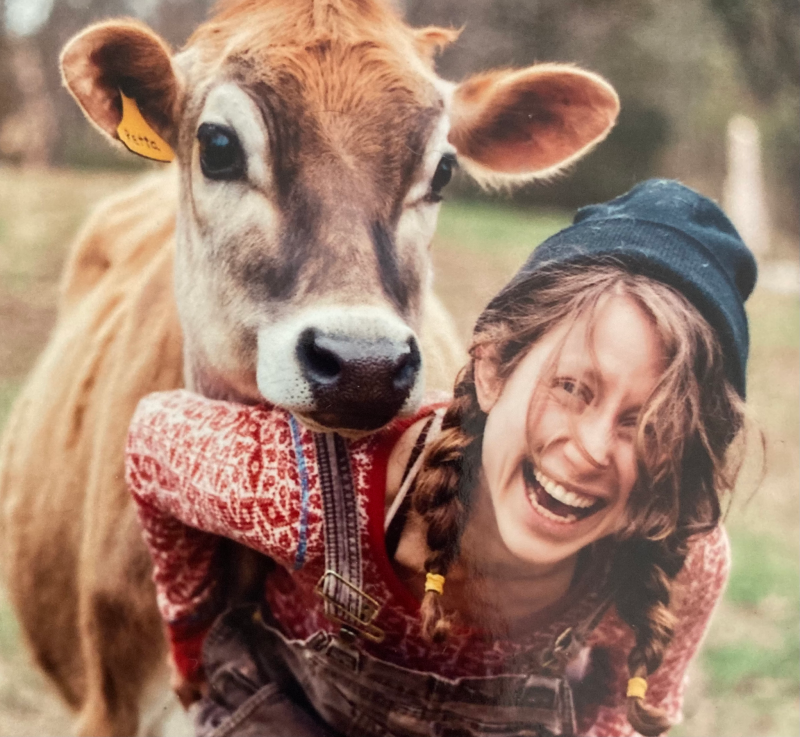 Nellie with braids, a blue beanie cap, and red patterned shirt with a cow