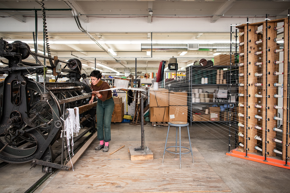 Interior of a weaving studio with a individual working on a large loom
