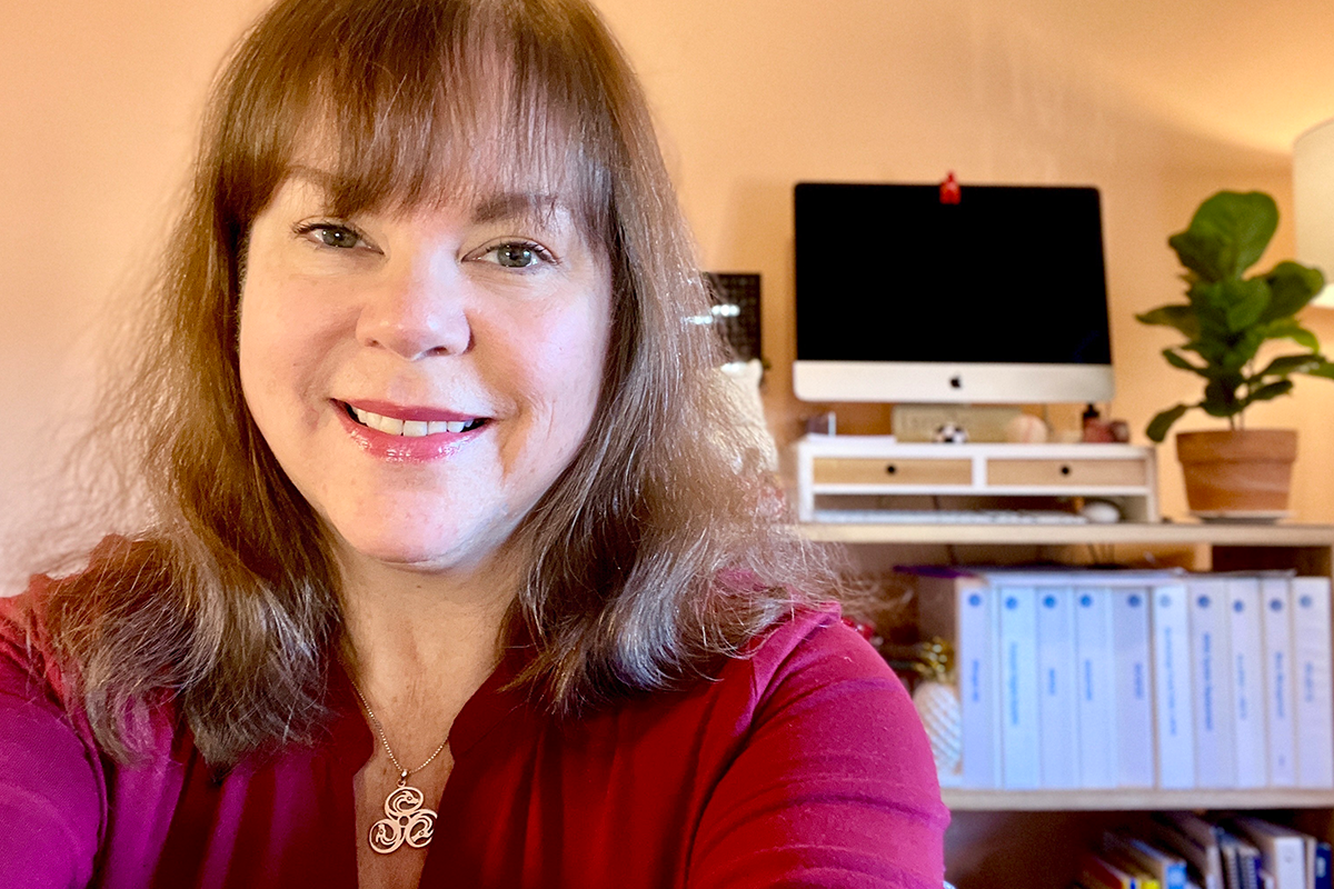 Maureen Young sits in her smiling office wearing a purple shirt