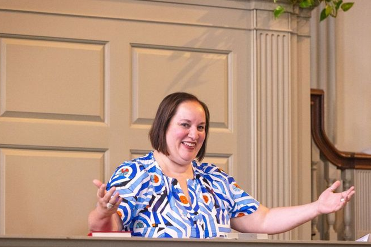 Sara Rothenberger, Associate Dean of Students stands at a podium in the First Baptist Church of America