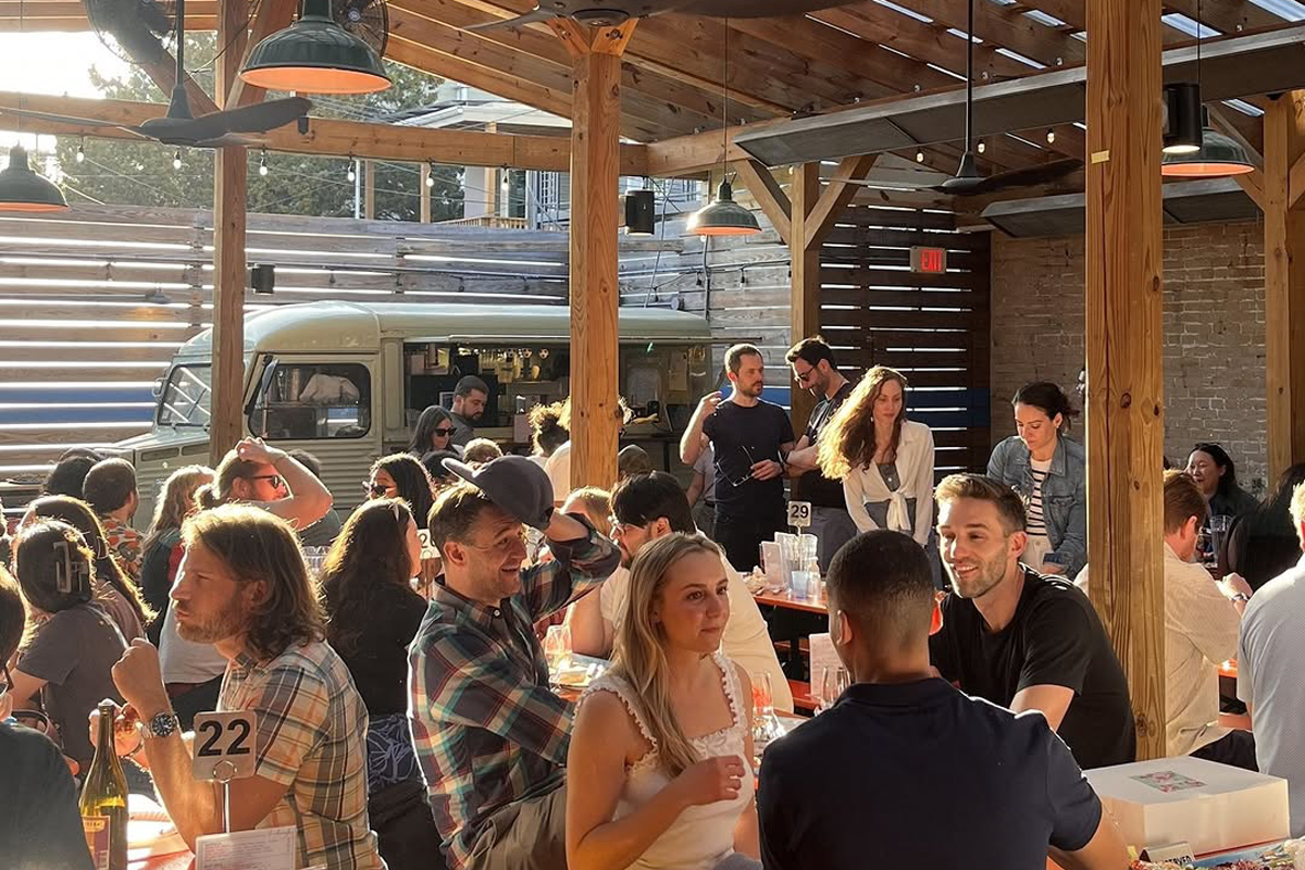 People gathered under a wood trellis in a beer garden