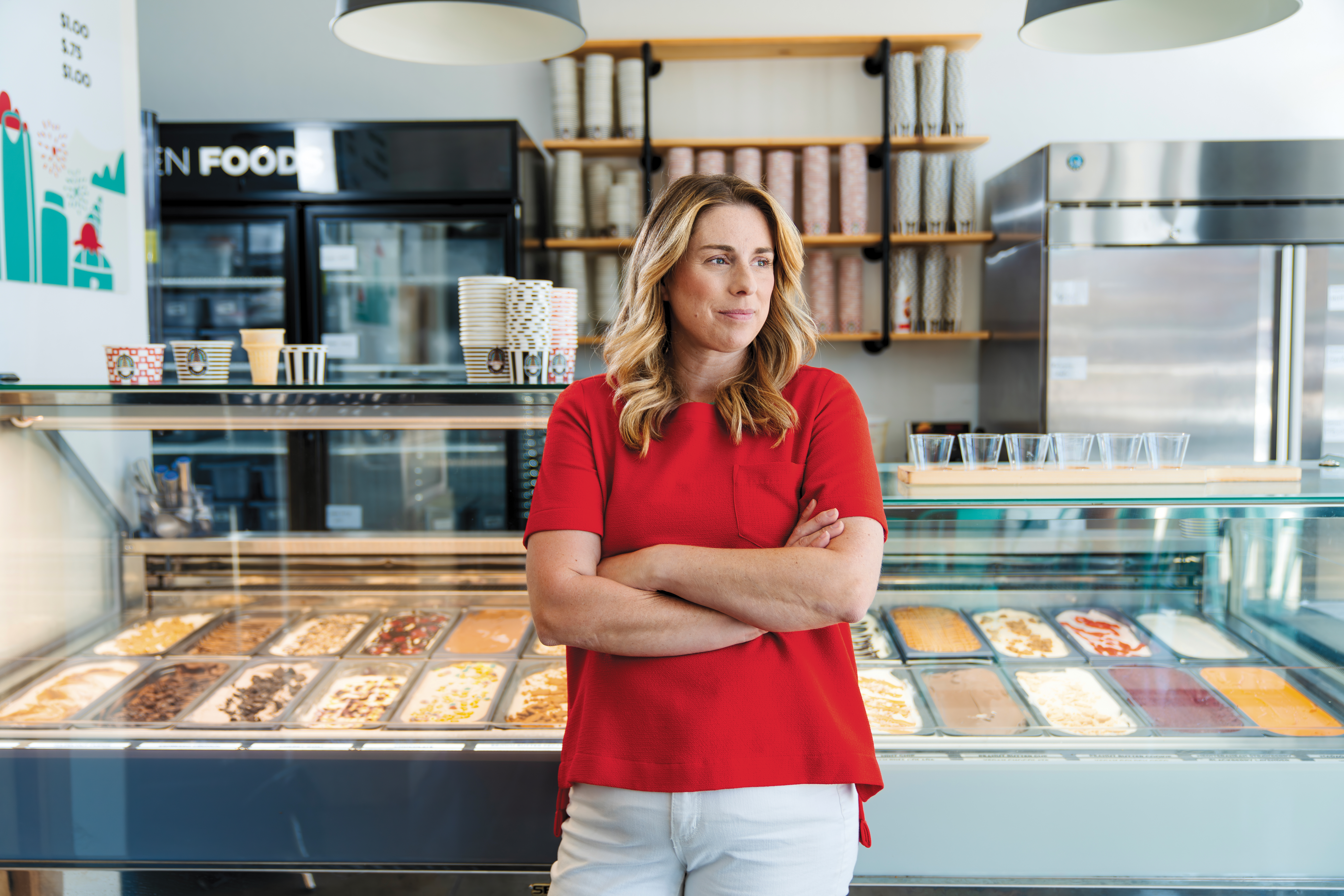 Angela Muir standing in her ice cream shop in front of a freezer case of ice cream