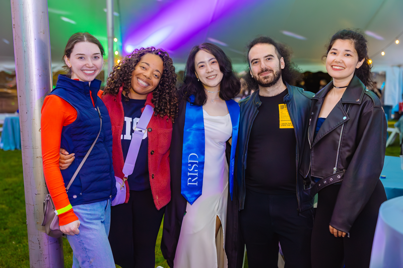 Alums and recent grads stand together smiling under a tent