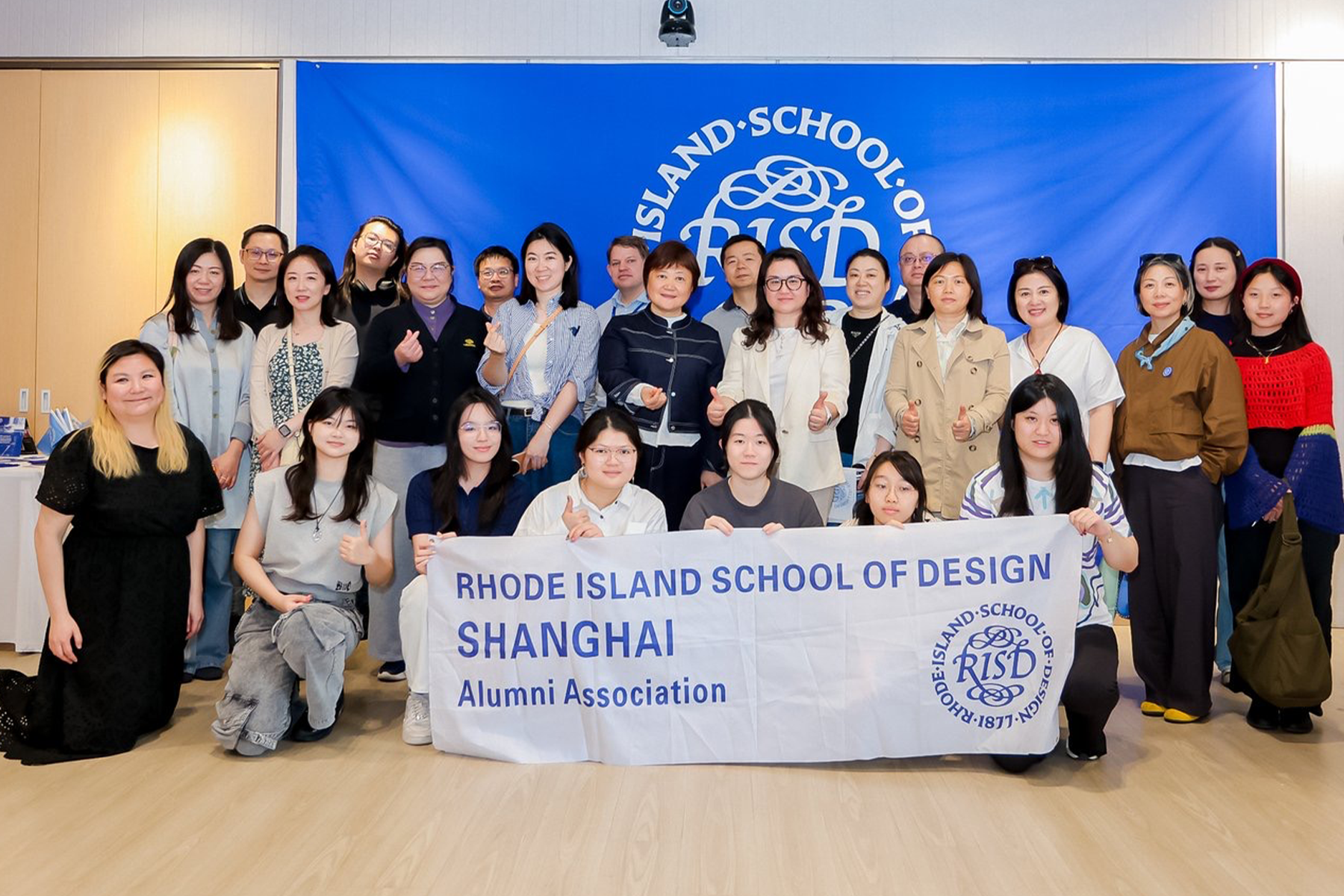 RISD Community members posed in front of a RISD Banner