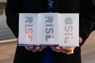 Hands holding lanterns laser cut to say RISD