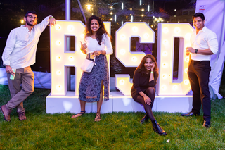 Alumni standing in front of a lit sign spelling RISD