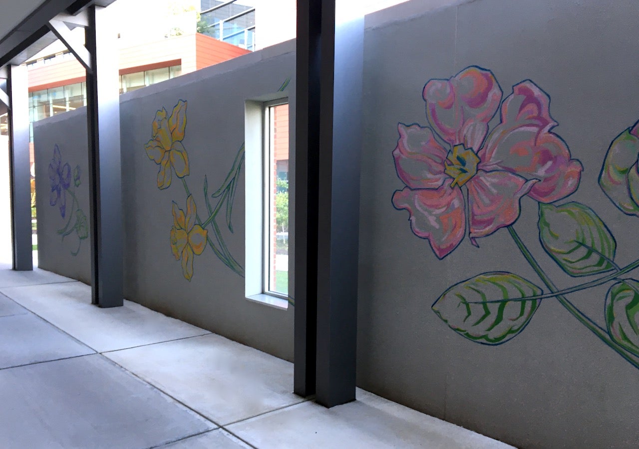 A photograph of the mural Flower Walk showing a wild rose in the foreground.